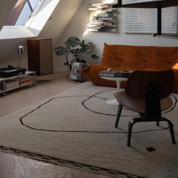 Stylish rug in beige with black lines as an accent in retro-style living room.